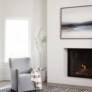 home staged photo with swivel chair next to white wall fireplace.